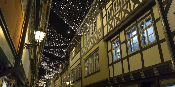 Abendliches Foto einer Brücke mit rechts und links Häusern, zwischen den Häusern hängen Lichterketten