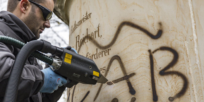 Ein Mann entfernt das Graffiti am Denkmal mit einem Laser