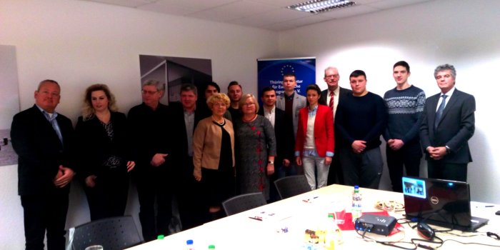 Foto: Impulsregion-Thüringenauftakt Arbeit 4.0 © Stadtverwaltung Erfurt Zahlreiche Menschen stehen in einem Raum nebeneinander postiert. Im Hintergrund ist ein Roll-up mit einer EU-Flagge.