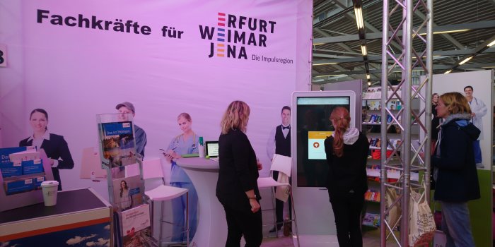 Messestand Impulsregion mit Personal und 2 Interessenten 