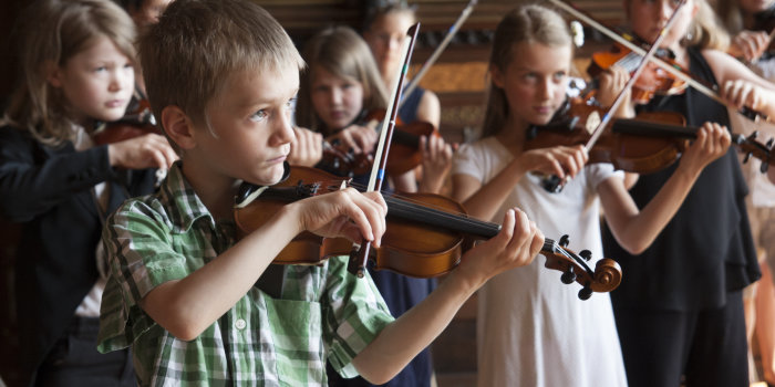 Mädchen und Jungen spielen auf Streichinstrumenten