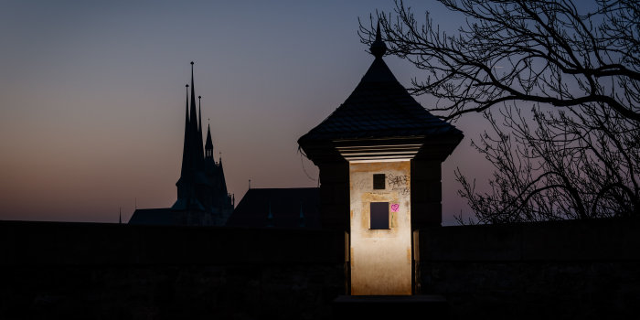 Foto: Petersberg bei Nacht © Stadtverwaltung Erfurt/S. Bauerschmidt Nächtliches Bild eines beleuchteten Turms des Petersbergs mit deutlich erkennbarem Graffiti, im Hintergrund der Dom