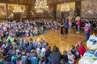 sehr viele Kinder auf dem Boden sitzend im Festsaal