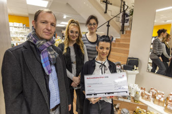 drei Frauen und ein Herr in einem Geschäft mit Check in der Hand