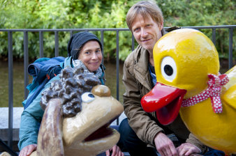 Ein Mann und eine Frau neben Figuren einer Ente und eines Hundes