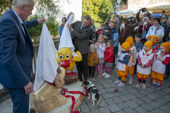 ZWei Männer entfernen ein weißes Tuch von zwei Figuren.