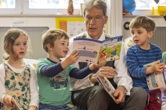 älterer Mann liest für Kleinkinder