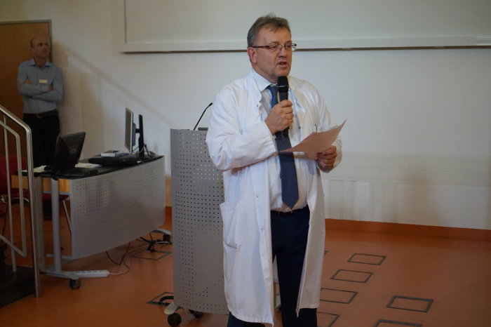 Chefarzt der Klinik für Kinderchirurgie am Helios Klinikum Erfurt Mann in weißem Kittel mit Mikrofon und Blättern in den Händen schaut ins Publikum.