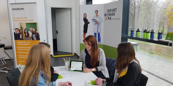 Vier junge Frauen sitzen an einem Tisch in einem Beratungsgespräch. 