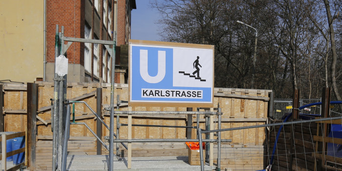 Auf einer Baustelle ist ein Schild errichtet mit dem Hinweis auf eine U-Bahn-Station mit dem Namen Karlstraße