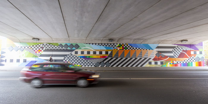 Eine bunt gestaltete Wand, vor der ein Auto fährt