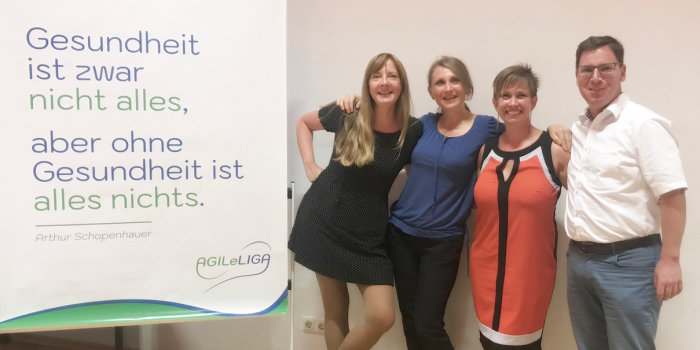 Foto: AgileLiga in M6 © AgileLiga Vier Menschen stehen neben einem Plakat