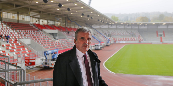 Ein Mann steht auf der Zuschauertribüne eines leeren Stadions