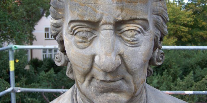 Foto: Reichart-Denkmal © Nüthen Restaurierungen Der Kopf eines historischen Denkmals, im Hintergrund ist ein Gerüst zu sehen.