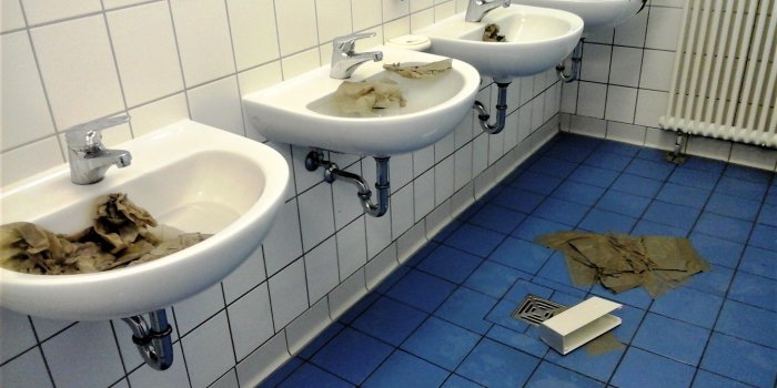 Mehrere Waschbecken, die mit Wasser befüllt und Papier verstopft wurden.