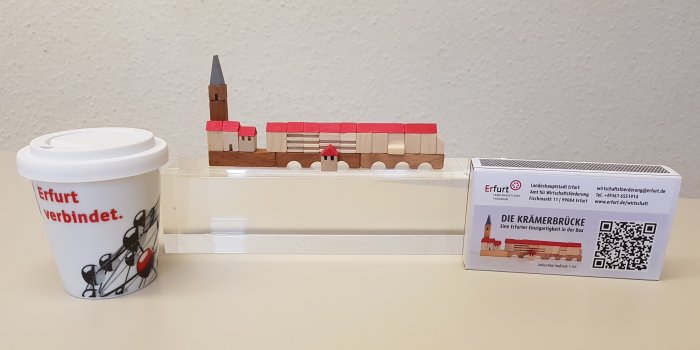 Ein Espressobecher, ein Miniaturmodell der Krämerbrücke aus Holz und die Verpackung als Streichholzschachtel. 
