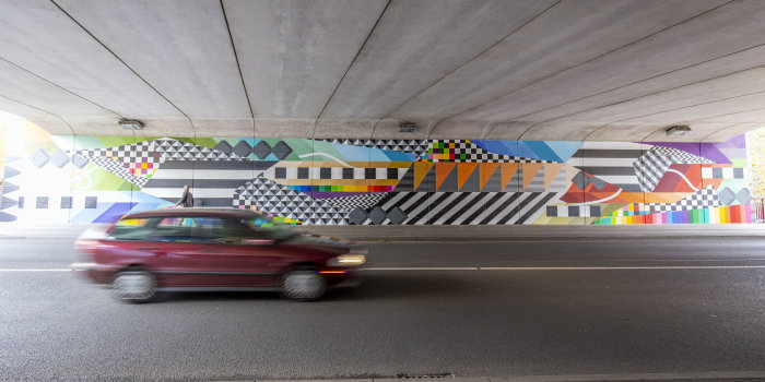 Eine bunt gestaltete Wand, vor der ein Auto fährt