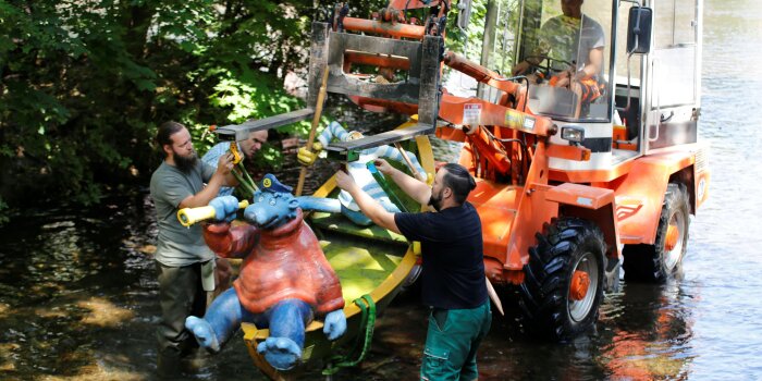 Arbeiter heben mit einem Stapler die Figur aus dem Wasser