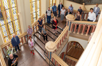 Frauen und Männer stehen im Treppenhaus des Rathauses