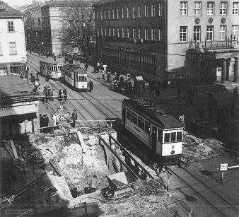 Eine halbseitig eingestürzte Brücke,auf der anderen Brückenseite fährt eine Straßenbahn.