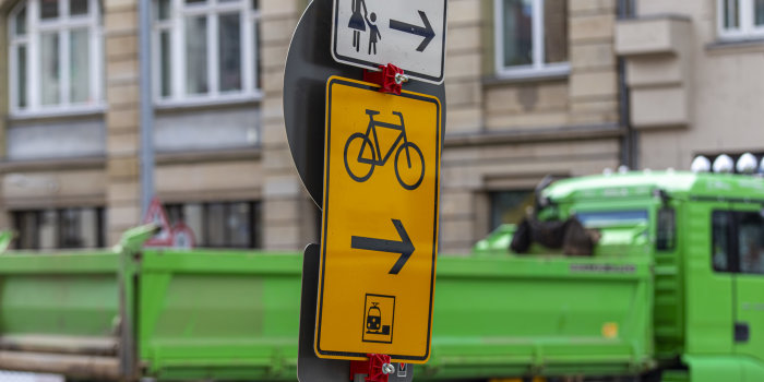 Vor einem LKW stehen zwei Hinweisschilder, die auf Umleitungen hinweisen.