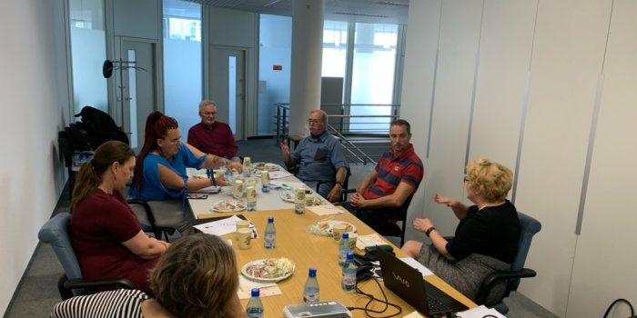 Foto: Arbeitsgruppe Erasmus+ © Stadtverwaltung Erfurt Eine Gruppe aus 7 Menschen sitzt mit Abstand zueinander an einem Tisch.