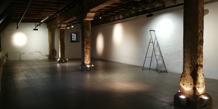 ein leerer Ausstellungsraum mit Säulen und Deckenbalken aus Holz