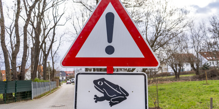 Ein dreieckiges Warnschild mit Ausrufezeichen und einem ergänzenden Schild mit einer Kröte