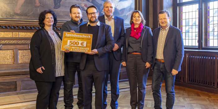 Vier Männer und zwei Frauen präsentieren einen Spendenscheck über 500 Euro