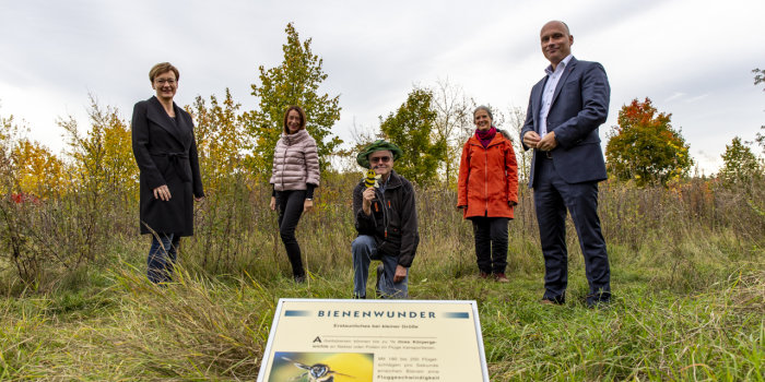 Foto: Stadtnaturpreis für den Wiesenhügel © Stadtverwaltung Erfurt Auf einer Wiese stehen drei Frauen und ein Mann, in der Mitte sitzt ein Mann.