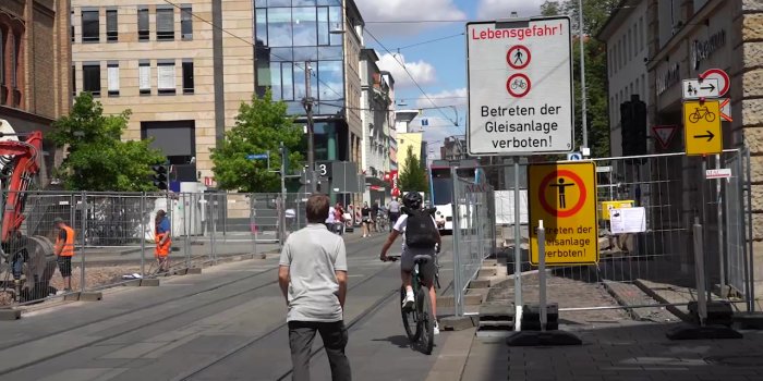 Menschen überqueren zu Fuß und mit dem Rad die Gleise in einer Baustelle