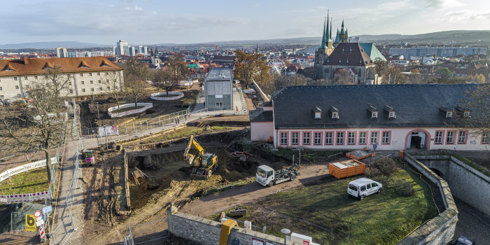 Luftbild auf Baustelle mit Häuserensemble und Mauern; im Hintergrund Altstadt von Erfurt