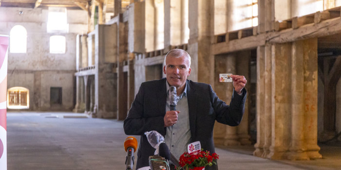 der Erfurter Oberbürgermeister präsentiert im Innenraum einer Kirche eine Buga-Dauerkarte im Chipkartenformat