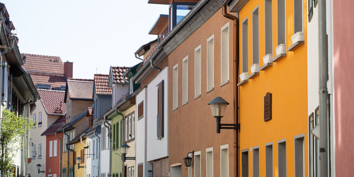 eine Reihe von Häusern mit verschiedenfarbigen Fassaden in einer schmalen Gasse