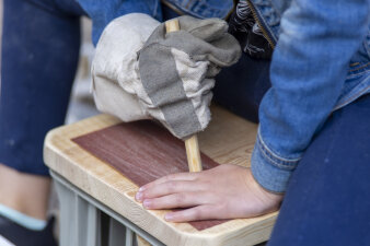 Ein Kind bearbeitet Holz mit Schleifpapier.