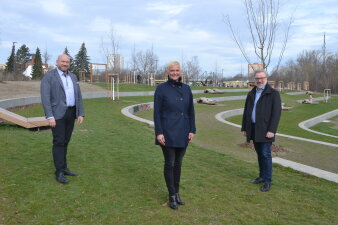 zwei Männer und eine Frau stehen in einem Park