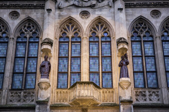 Zwei Statuen schmücken die Fassade eines neogotischen Gebäudes.