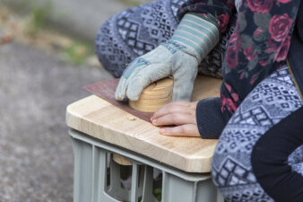 Ein Kind bearbeitet Holz mit Schleifpapier.