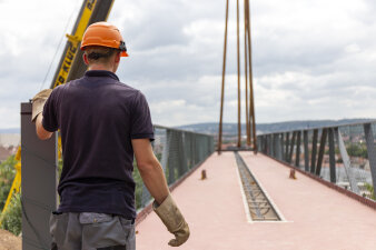 ein Bauarbeiter steht an einer Brücke