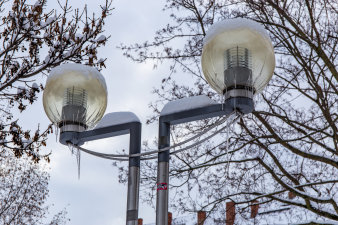 An der Kugel einer Straßenlaterne bilden sich Eiszapfen.