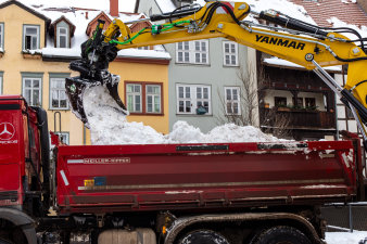 En Bagger lädt Schnee auf einen LKW.