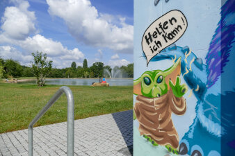 eine mit Graffiti mit Yoda-Motiv gestaltete Fassade, im Hintergrund ein Park mit Teich