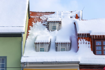 Dachgeschoss eines Hauses mit drei Fenstern, an denen Eiszapfen hängen