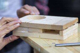 Kinderhände halten drei Scheiben Holz in der Hand. 