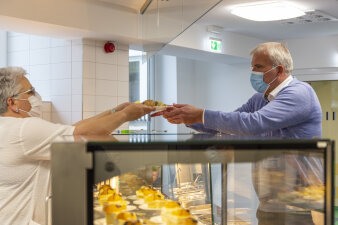 Eine Frau übergibt einem Mann einen Teller mit Essen.