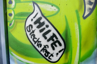eine mit Graffiti gestaltete Fassade, Motiv ist eine Sprechblase mit "Hilfe, ich steck fest"