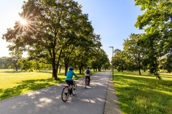 zwei Radfahrer fahren auf einem asphaltierten Weg durch einen Park