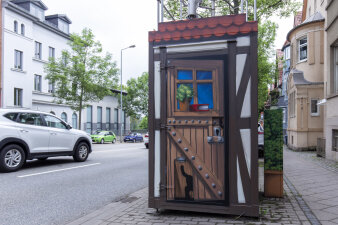 ein mit Graffiti gestaltetes Häuschen auf einem Gehweg an einer Straße