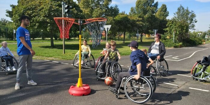 Kinder probieren ihre Fähigkeiten in einem Rollstuhl