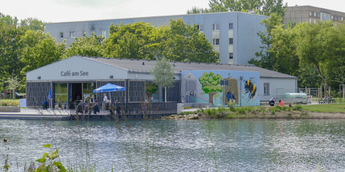 ein mit Graffiti gestaltetes, eingeschossiges Gebäude an einem Teich